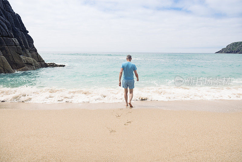 康沃尔，一名男子正走向Pedn Vounder海滩的海岸线。